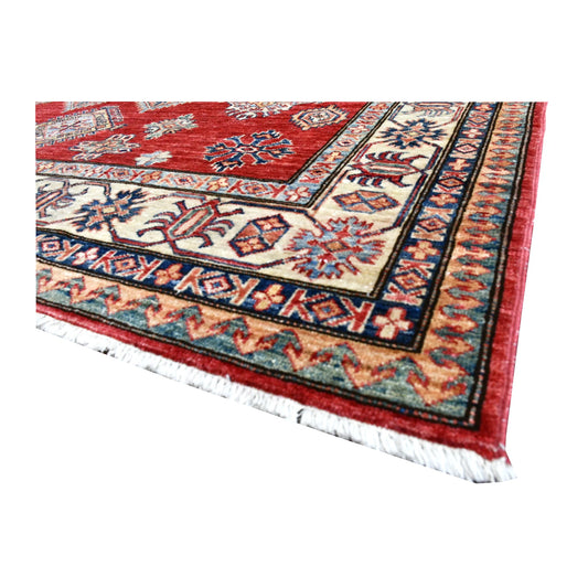 Angled corner detail of Afghan Super Kazak rug showing the broad ivory motif border, dark guard bands and ivory fringe