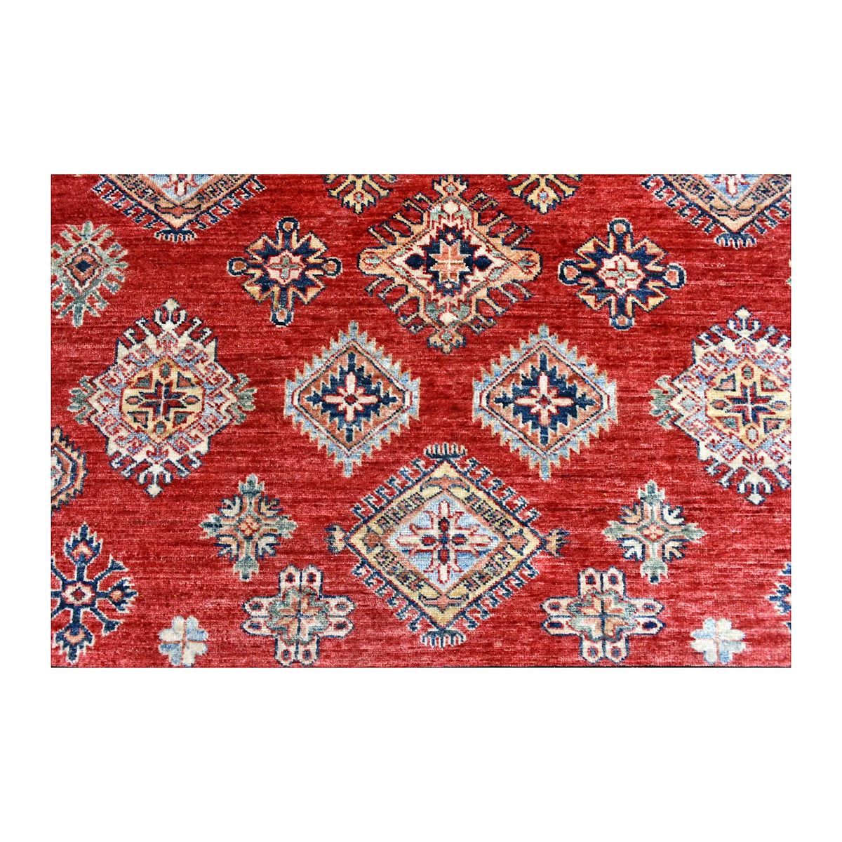 Close-up of the red field showing rows of blue, ivory, tan and muted green diamond motifs with smaller geometric ornaments