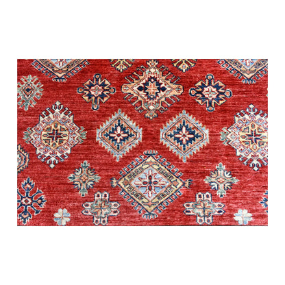 Close-up of the red field showing rows of blue, ivory, tan and muted green diamond motifs with smaller geometric ornaments