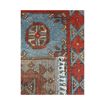 Folded corner detail of Afghan Turkoman blue wool rug showing the back, fringe and blue-red front pattern