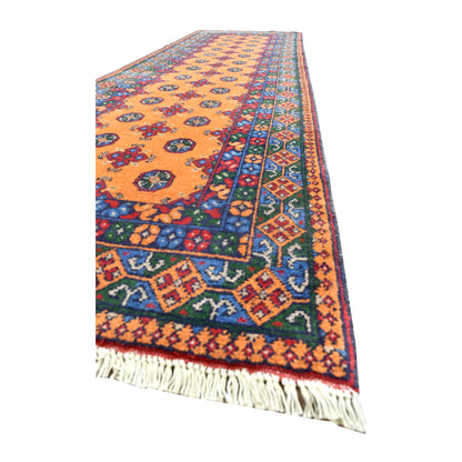 Angled view of Afghan Turkoman runner showing its golden field, richly patterned blue borders and pale fringe