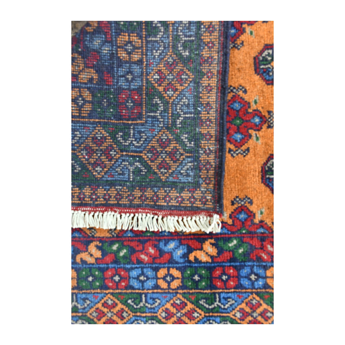 Folded-corner detail of Afghan Turkoman runner showing the patterned reverse beside its golden field, colourful border and pale fringe