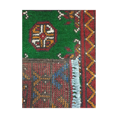 Folded corner detail of Afghan Turkoman green wool rug showing the back, fringe and green-red front pattern