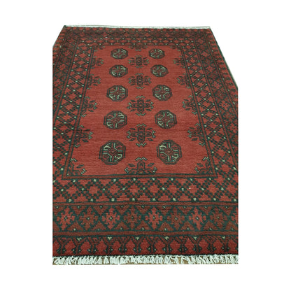 Angled full view of Afghan Turkoman wool rug showing red field, black border and cream geometric details