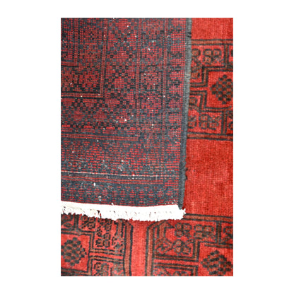 Folded-corner detail of Afghan Turkoman rug showing the reverse weave, red patterned front and ivory fringe