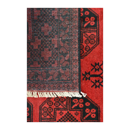 Folded-corner detail of Afghan Turkoman rug showing the reverse weave, red patterned front and pale fringe