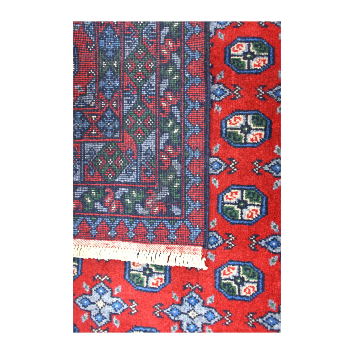 Folded-corner detail of Afghan Turkoman rug showing the reverse weave beside its red patterned front and white fringe