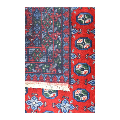 Folded-corner detail of Afghan Turkoman rug showing the reverse weave beside its red patterned front and white fringe
