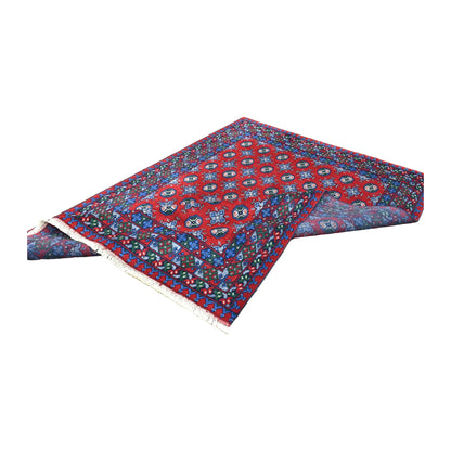 Folded view of Afghan Turkoman wool rug showing its red gul field, layered patterned borders and underside