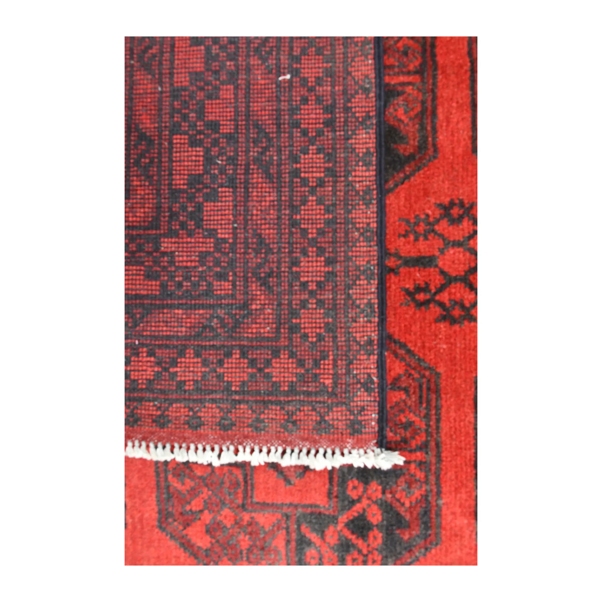 Folded-corner detail of Afghan Turkoman rug showing the patterned reverse weave, red front and white fringe