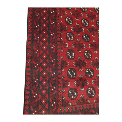 Border and field detail of Afghan Turkoman wool rug showing red pile, dark charcoal motifs and ivory accents