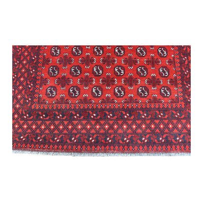 End-border detail of Afghan Turkoman rug showing red field motifs above a dark diamond lattice and white fringe