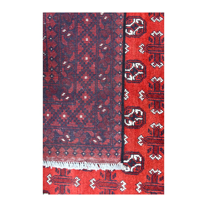 Folded-corner detail of Afghan Turkoman rug showing the patterned reverse beside its red front and white fringe