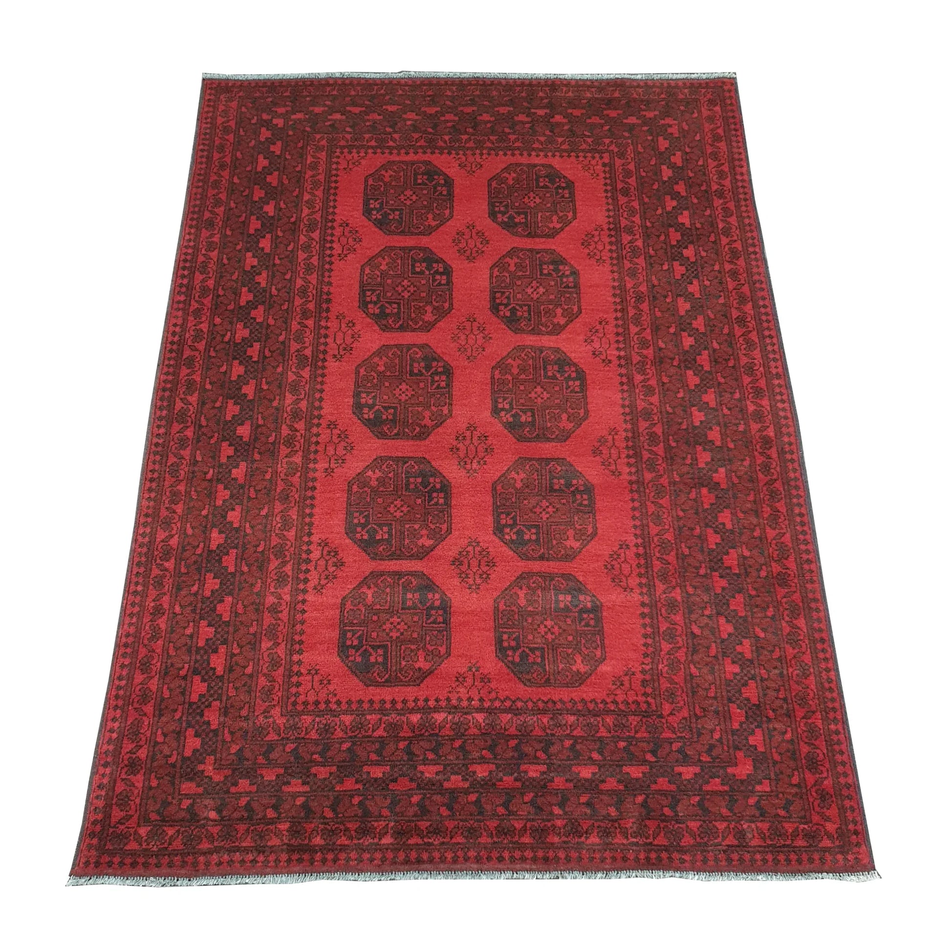 Angled view of Afghan Turkoman hand-knotted wool rug showing red field, wide border and ivory fringe, 240 x 176 cm