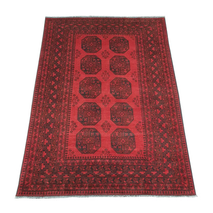 Angled view of Afghan Turkoman hand-knotted wool rug showing red field, wide border and ivory fringe, 240 x 176 cm