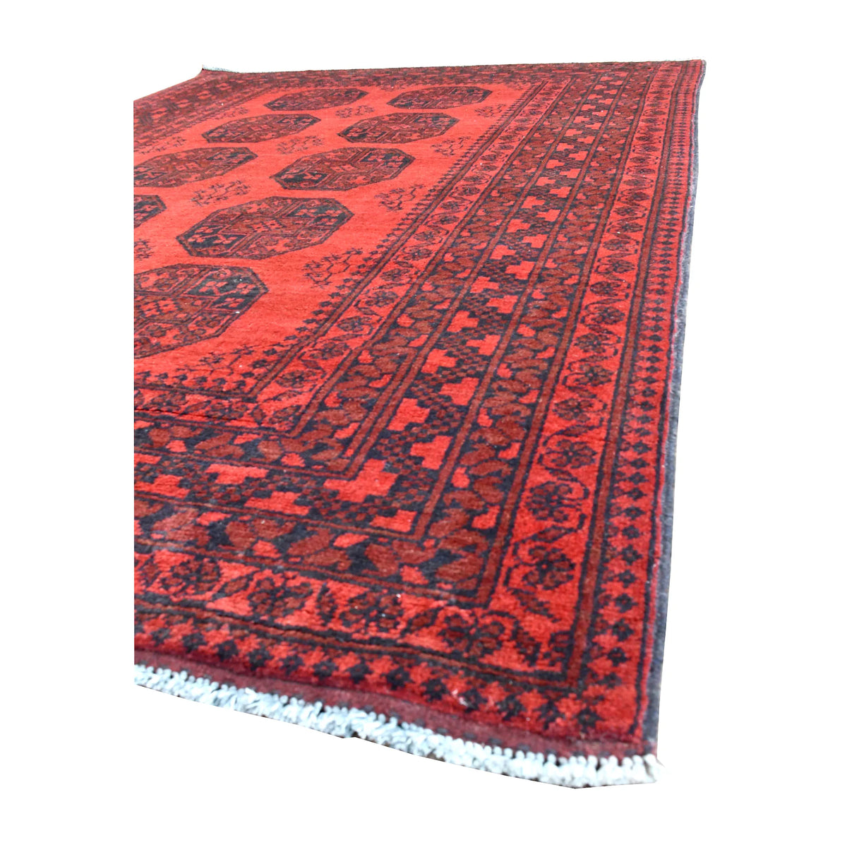 Angled view of Afghan Turkoman wool rug showing its large dark guls, layered burgundy border and white fringe