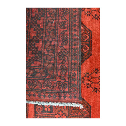 Folded-corner detail of Afghan Turkoman rug showing the reverse weave beside its red front, dark border and white fringe