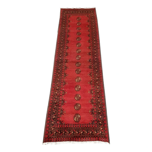 Full view of Afghan Turkoman hand-knotted wool runner rug with red field and repeated gul-style motifs, 235 x 69 cm