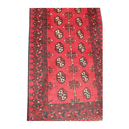 Border and field detail of Afghan Turkoman wool runner rug showing red pile, dark charcoal patterning and ivory accents
