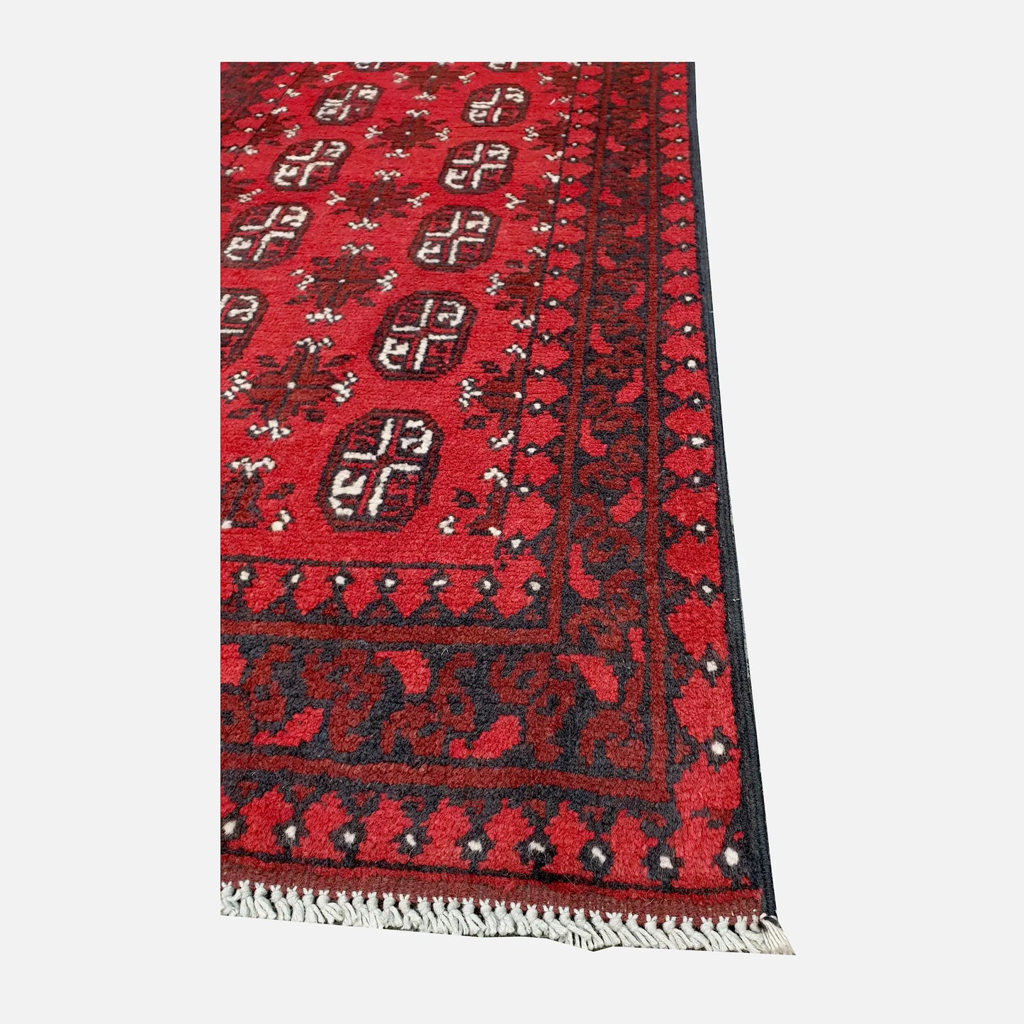 Angled corner and fringe view of Afghan Turkoman hand-knotted wool runner rug showing red field, geometric border and light fringe