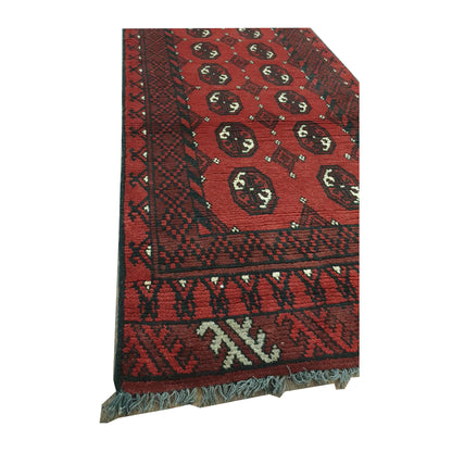 Angled fringe detail of Afghan Turkoman wool runner rug showing red field, dark border and hand-knotted texture