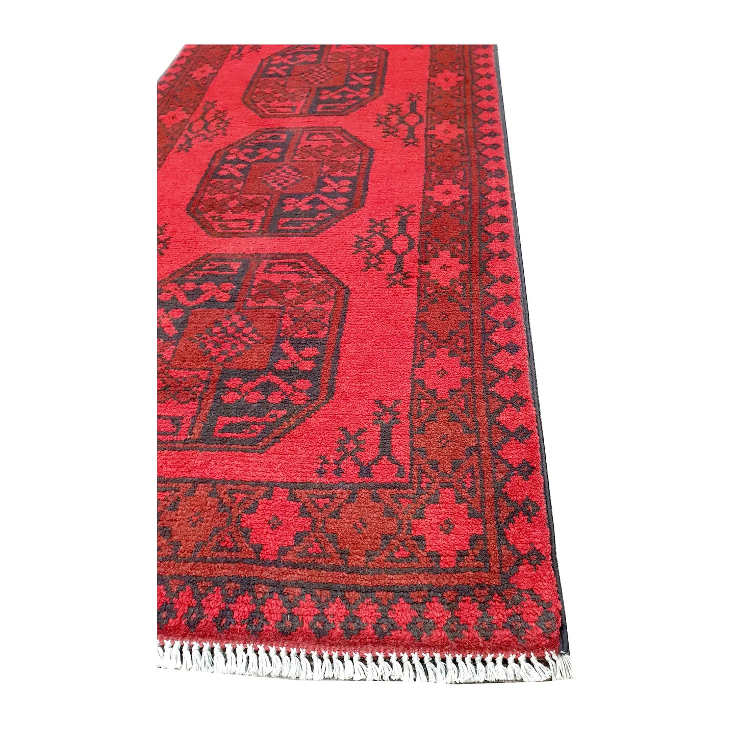 Angled corner and fringe view of Afghan Turkoman wool runner rug showing red field, geometric border and light fringe