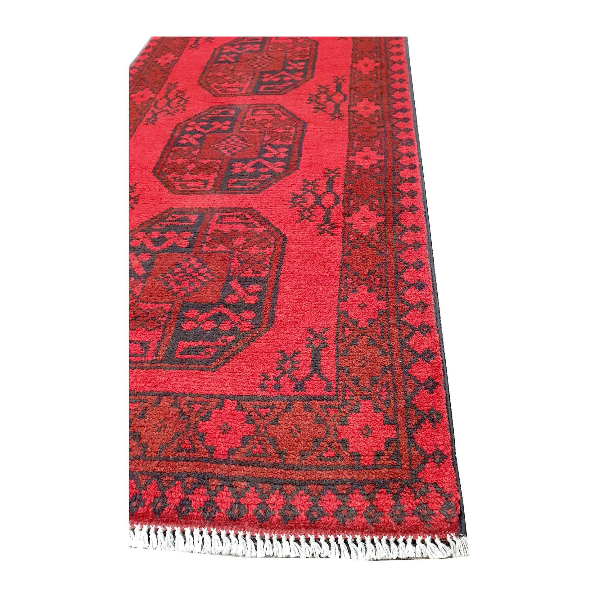 Angled corner and fringe view of Afghan Turkoman wool runner rug showing red field, geometric border and light fringe