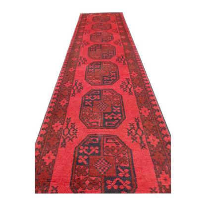 Angled field view of Afghan Turkoman hand-knotted wool runner rug showing repeated medallions and dark border detail