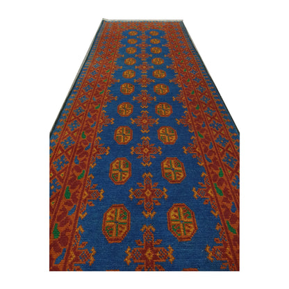 Angled view of Afghan Turkoman wool runner rug showing blue field, orange motifs and geometric border