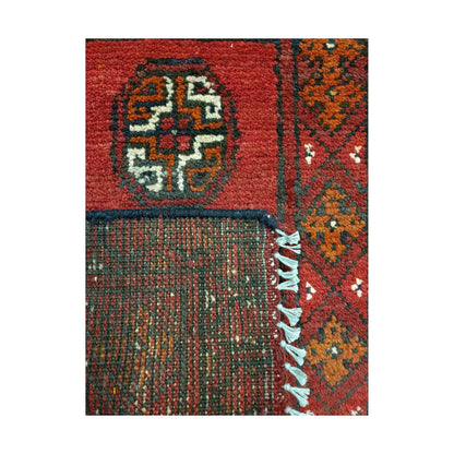 Folded corner detail of Afghan Turkoman red wool rug showing the back, fringe and red front pattern