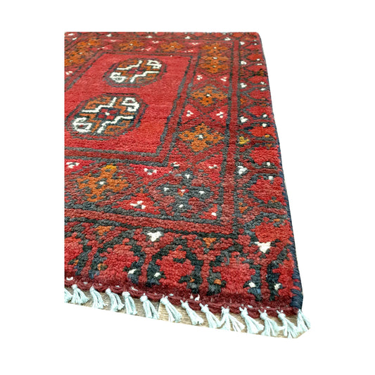 Fringe and border detail of Afghan Turkoman red wool rug showing dark edging, red field and tribal motifs