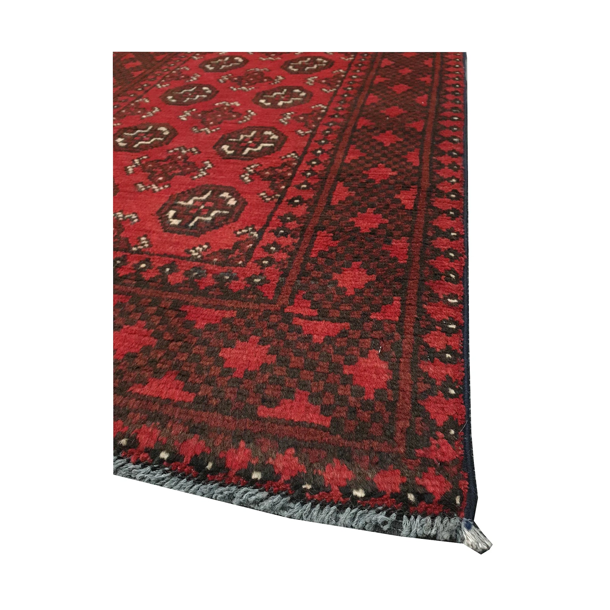 Angled field and border detail of Afghan Turkoman rug showing red wool pile, gul motifs and dark geometric edging