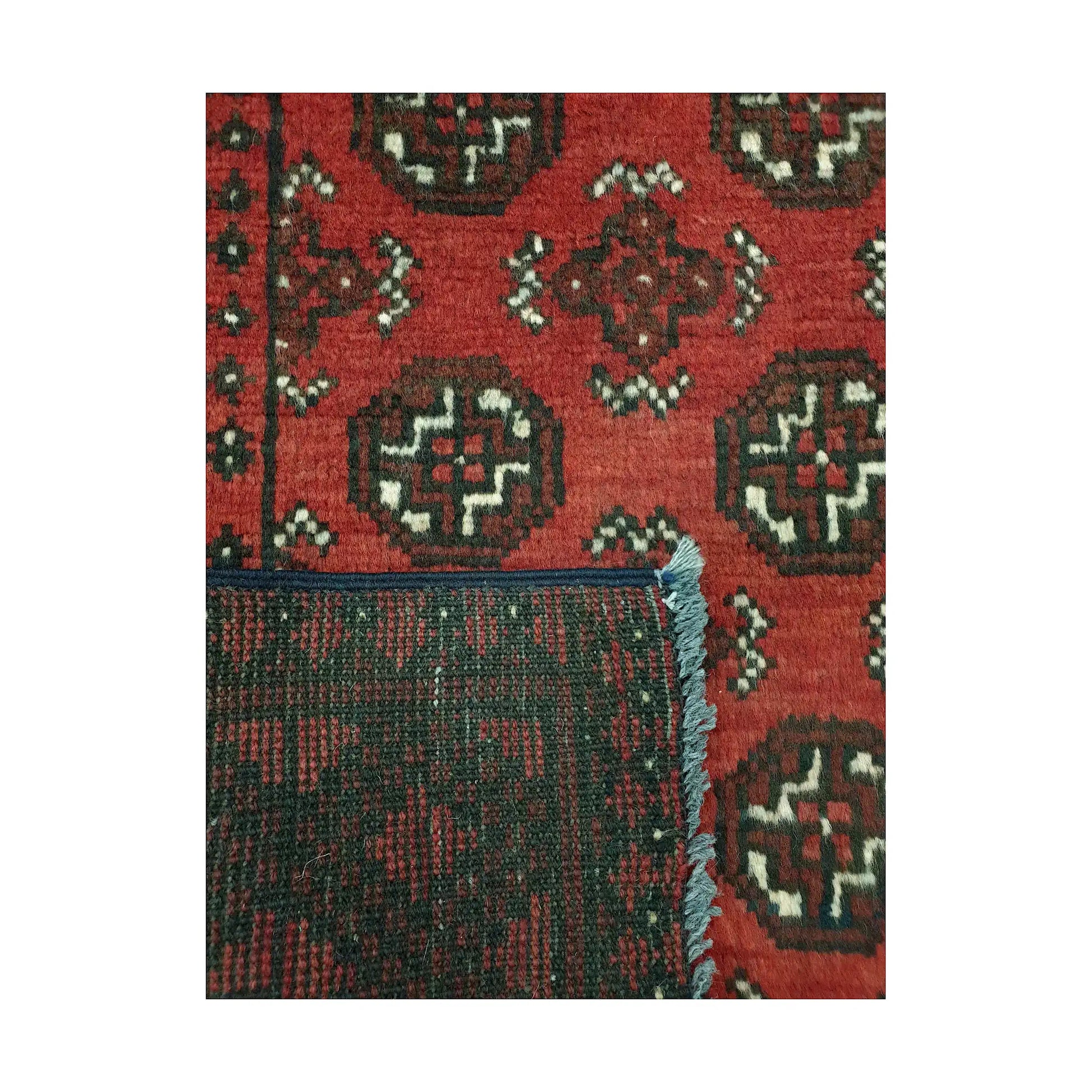 Folded corner detail of Afghan Turkoman rug showing the back of the rug and red gul pattern on the front