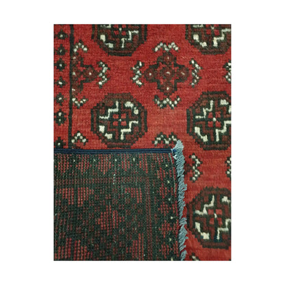 Folded corner detail of Afghan Turkoman rug showing the back of the rug and red gul pattern on the front