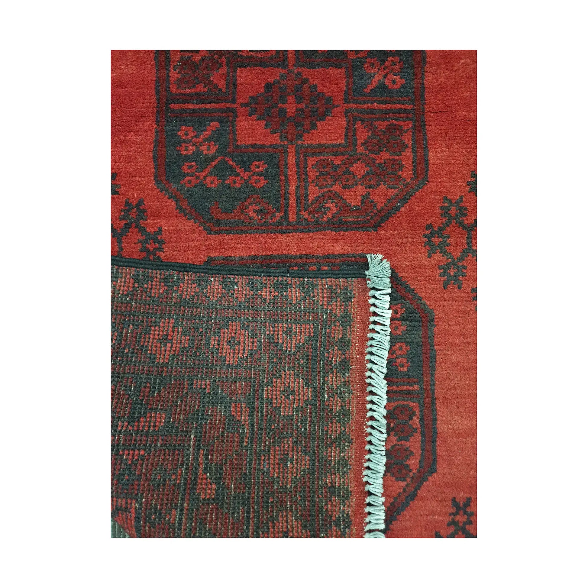 Folded corner detail of Afghan Turkoman rug showing the back of the rug, fringe and red front pattern