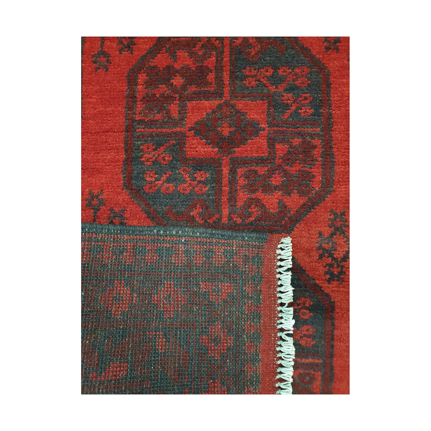 Folded corner detail of Afghan Turkoman rug showing the back of the rug, fringe and red front pattern
