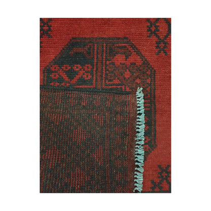 Folded corner detail of Afghan Turkoman rug showing the back of the rug, fringe and red front pattern