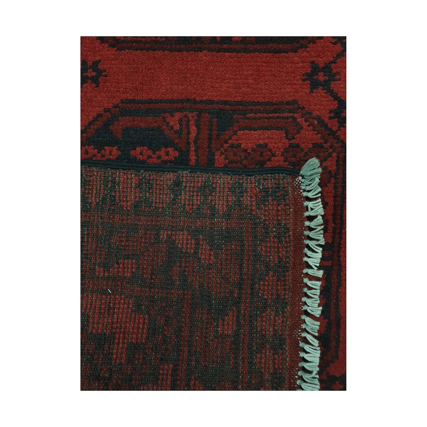 Folded corner detail of Afghan Turkoman rug showing the back of the rug, fringe and red front pattern