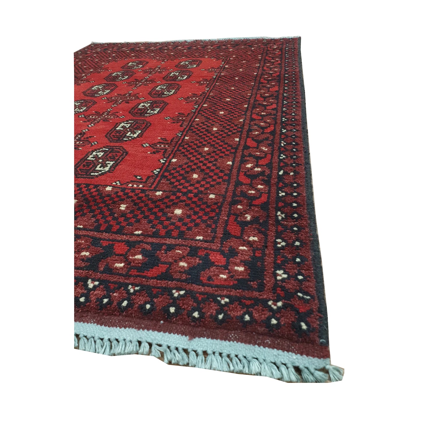 Angled border and fringe detail of Afghan Turkoman rug showing red wool pile, dark geometric edging and fringe