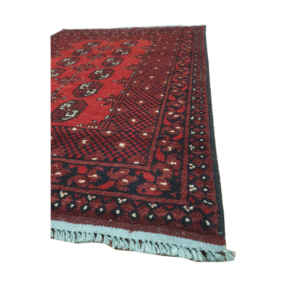 Angled border and fringe detail of Afghan Turkoman rug showing red wool pile, dark geometric edging and fringe