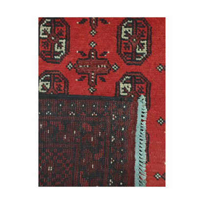 Folded corner detail of Afghan Turkoman rug showing the back of the rug, fringe and red front pattern
