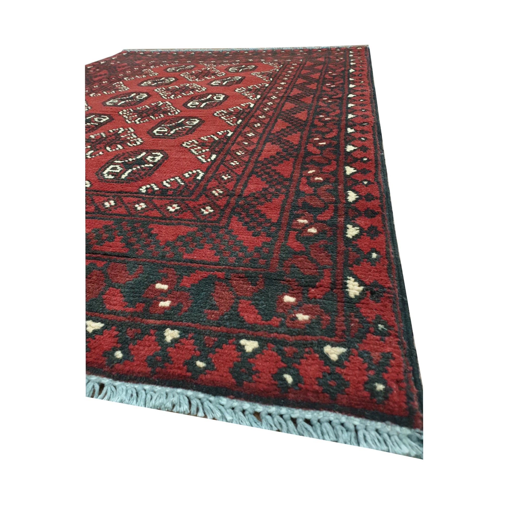 Angled border and fringe detail of Afghan Turkoman rug showing red wool pile, dark geometric edging and fringe