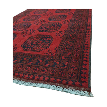 Angled border and fringe detail of Afghan Turkoman rug showing red wool pile, charcoal motifs and geometric edging