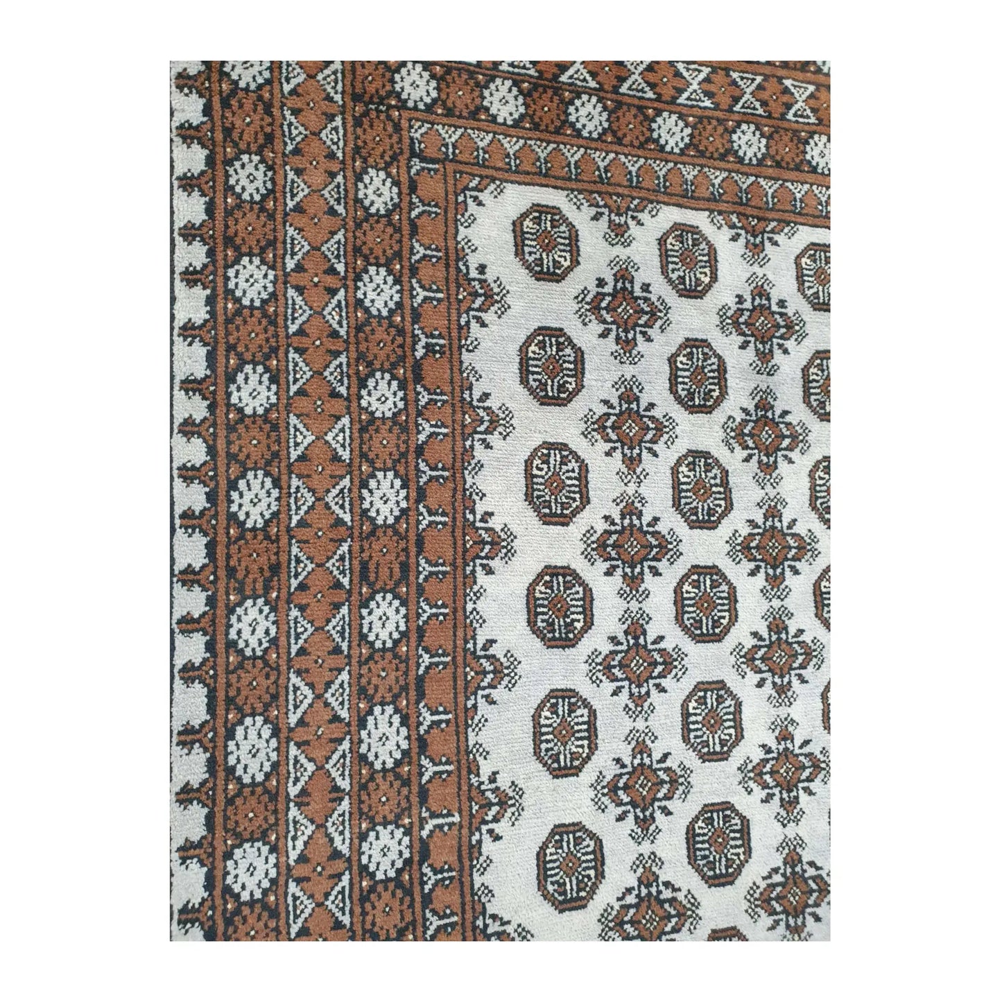 Close-up of Afghan Turkoman rug showing the off-white gul-patterned field and layered side border