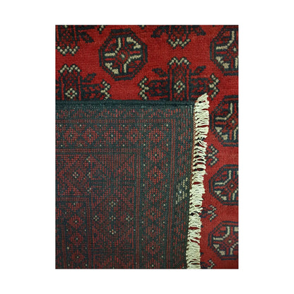 Folded corner detail of Afghan Turkoman rug showing the back of the rug, fringe and deep red front pattern