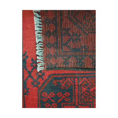 Folded corner detail of Afghan Turkoman runner rug showing the back of the rug, fringe and red front pattern