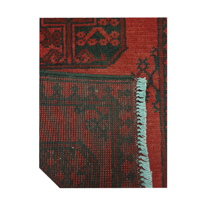 Folded corner detail of Afghan Turkoman runner rug showing the back of the rug, fringe and red front pattern