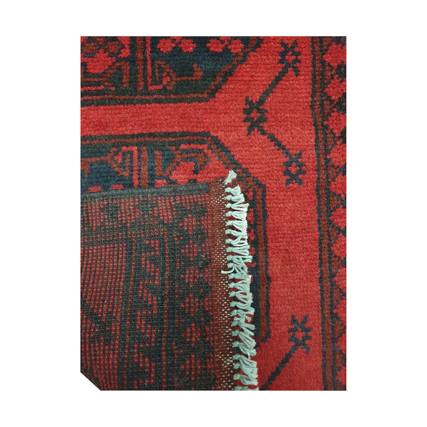 Folded corner detail of Afghan Turkoman runner rug showing the back of the rug, fringe and red front pattern