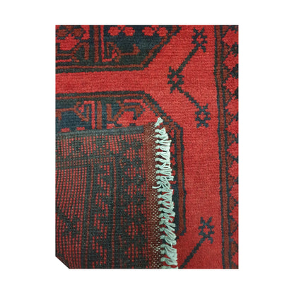 Folded corner detail of Afghan Turkoman runner rug showing the back of the rug, fringe and red front pattern