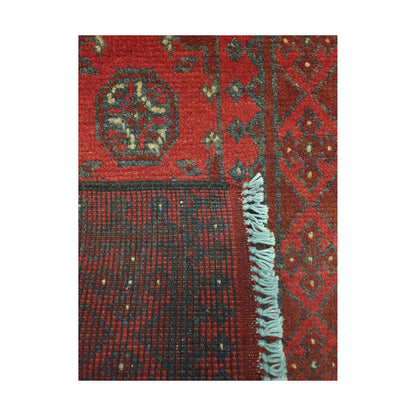 Folded corner detail of Afghan Turkoman runner rug showing the back of the rug, fringe and red front pattern